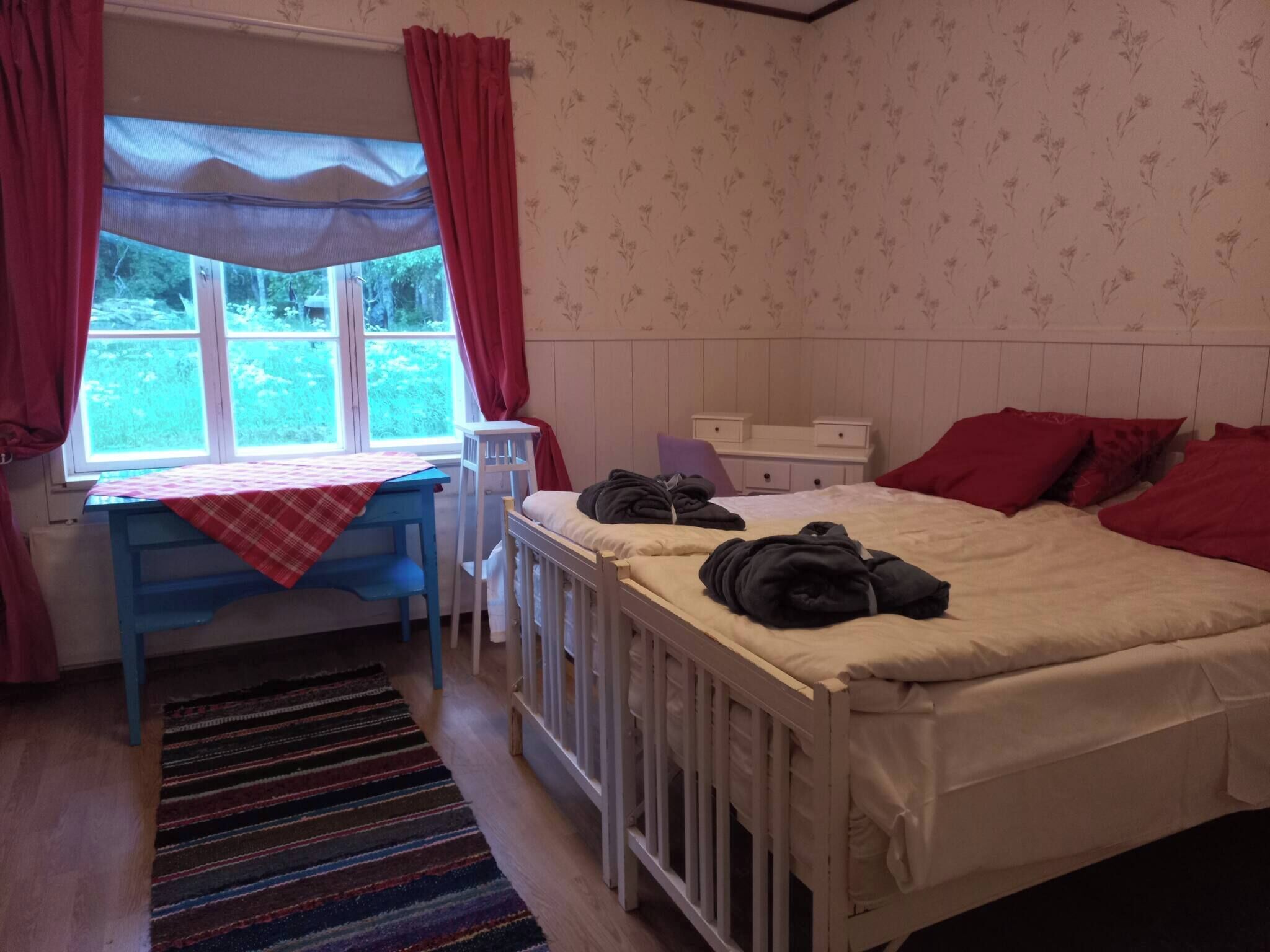 Ein Schlafzimmer mit einem Bett, einem Schreibtisch und einem Fenster mit Vorhängen.