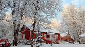 A red house surrounded by snow-covered trees.