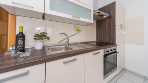 A modern kitchen with a stainless steel sink, a built-in oven, and a potted plant. - Apartments Jukic (Sveti Filip i Jakov)