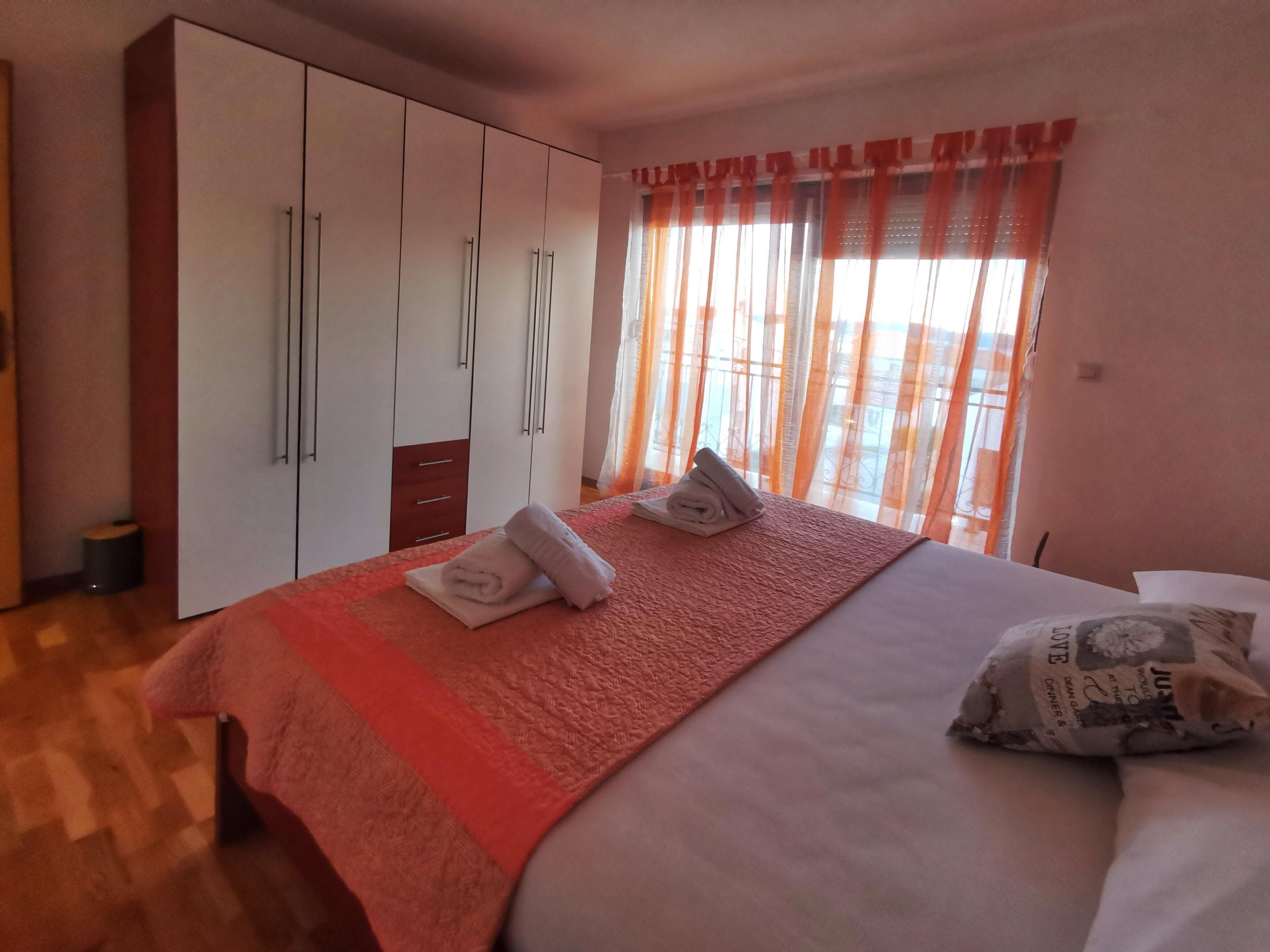 A hotel room with a bed, a wardrobe, and a window with curtains.