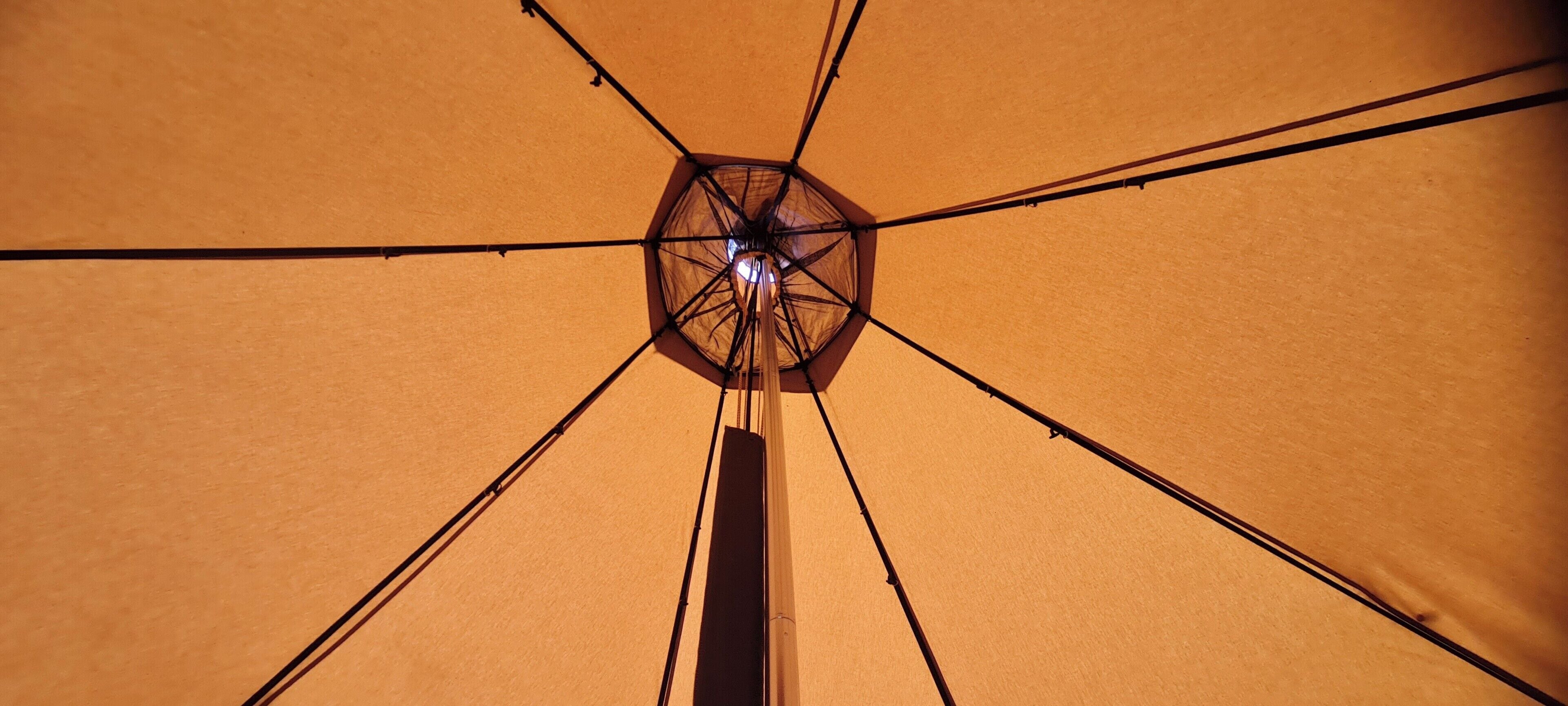 Un soffitto con un lampadario centrale e travi a raggiera.