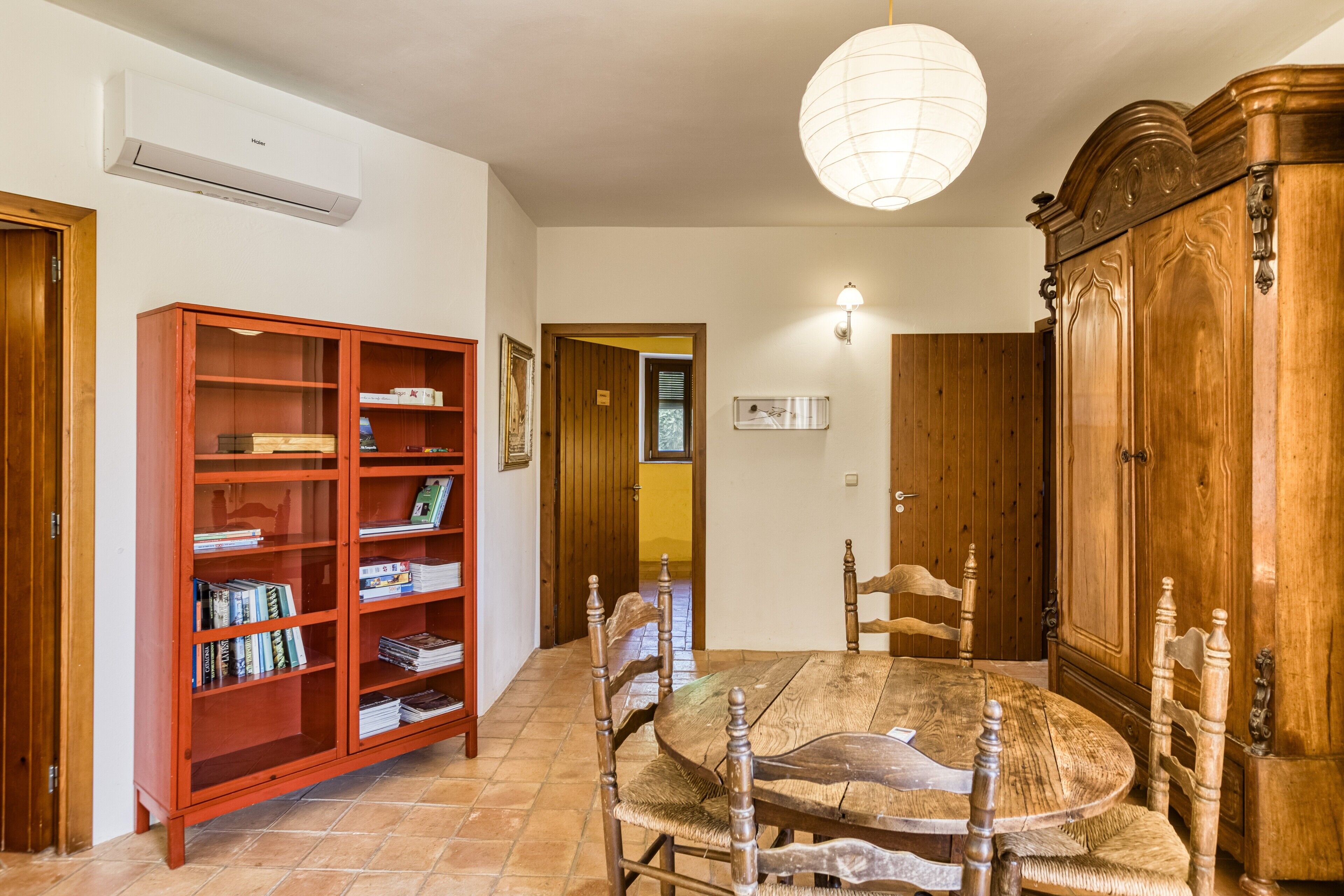 A dining area with a wooden table, chairs, a bookshelf, and a cabinet.