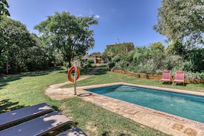 A swimming pool with a tiled edge, surrounded by a grassy area and trees. - Room 'Sempreviva' with Shared Pool, Wi-Fi and Air Conditioning (Borrassà)
