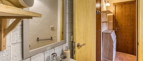 A bathroom with a white sink, a mirror, a hairdryer, and a wooden door.