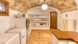 A kitchen with a brick ceiling, white appliances, and a wooden counter. - Room 'Sempreviva' with Shared Pool, Wi-Fi and Air Conditioning (Borrassà)