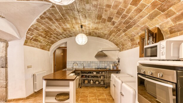 Una cocina con techo de ladrillo, electrodomésticos blancos y salpicadero de azulejos.