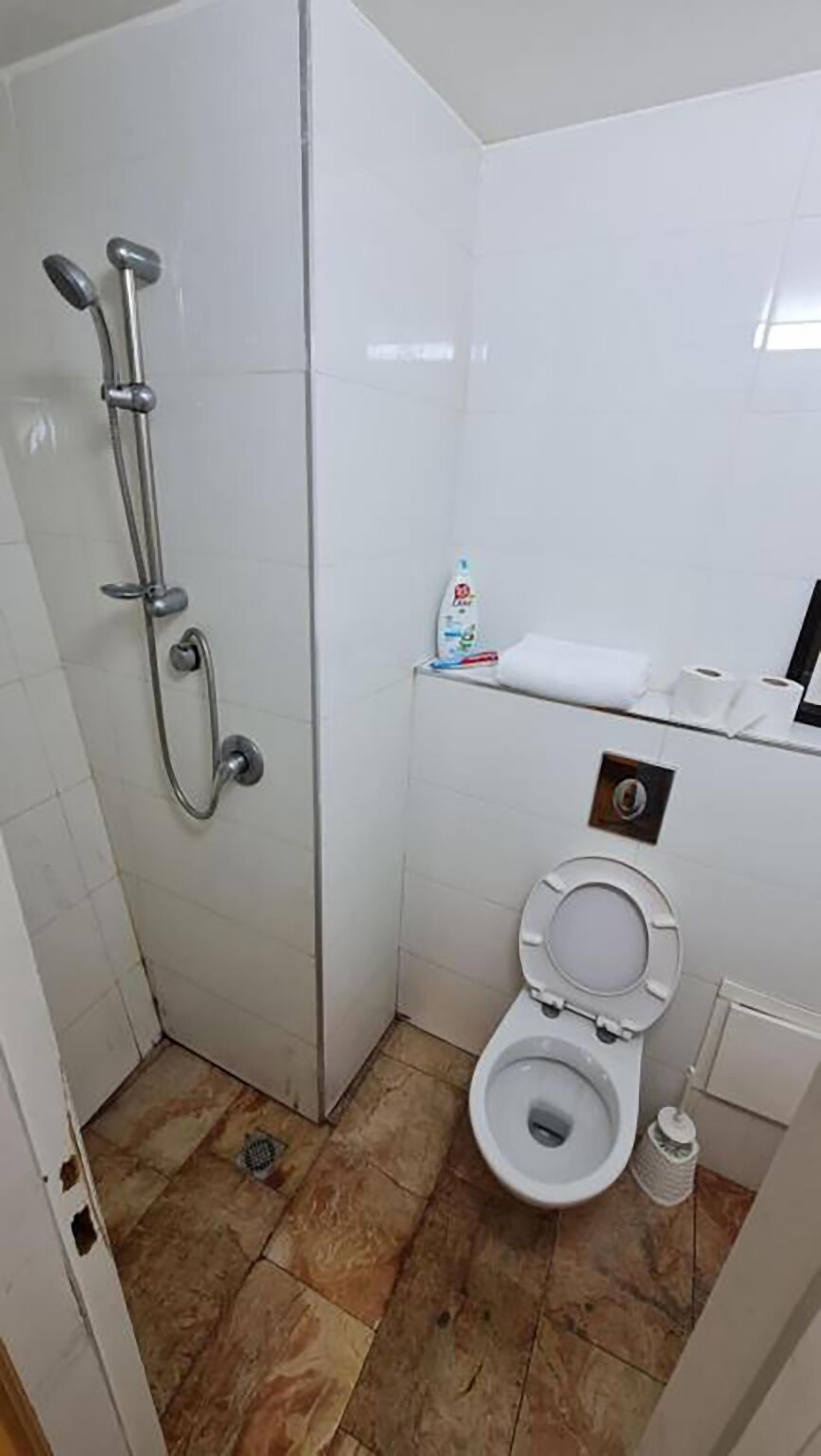 Un baño pequeño con ducha, inodoro y lavamanos.