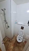 Un baño pequeño con ducha, inodoro y lavamanos.