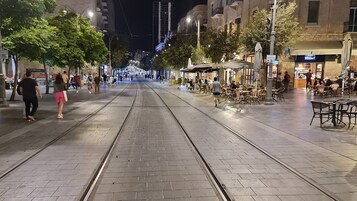 Una amplia calle peatonal con vías de tranvía, terrazas y cafés.