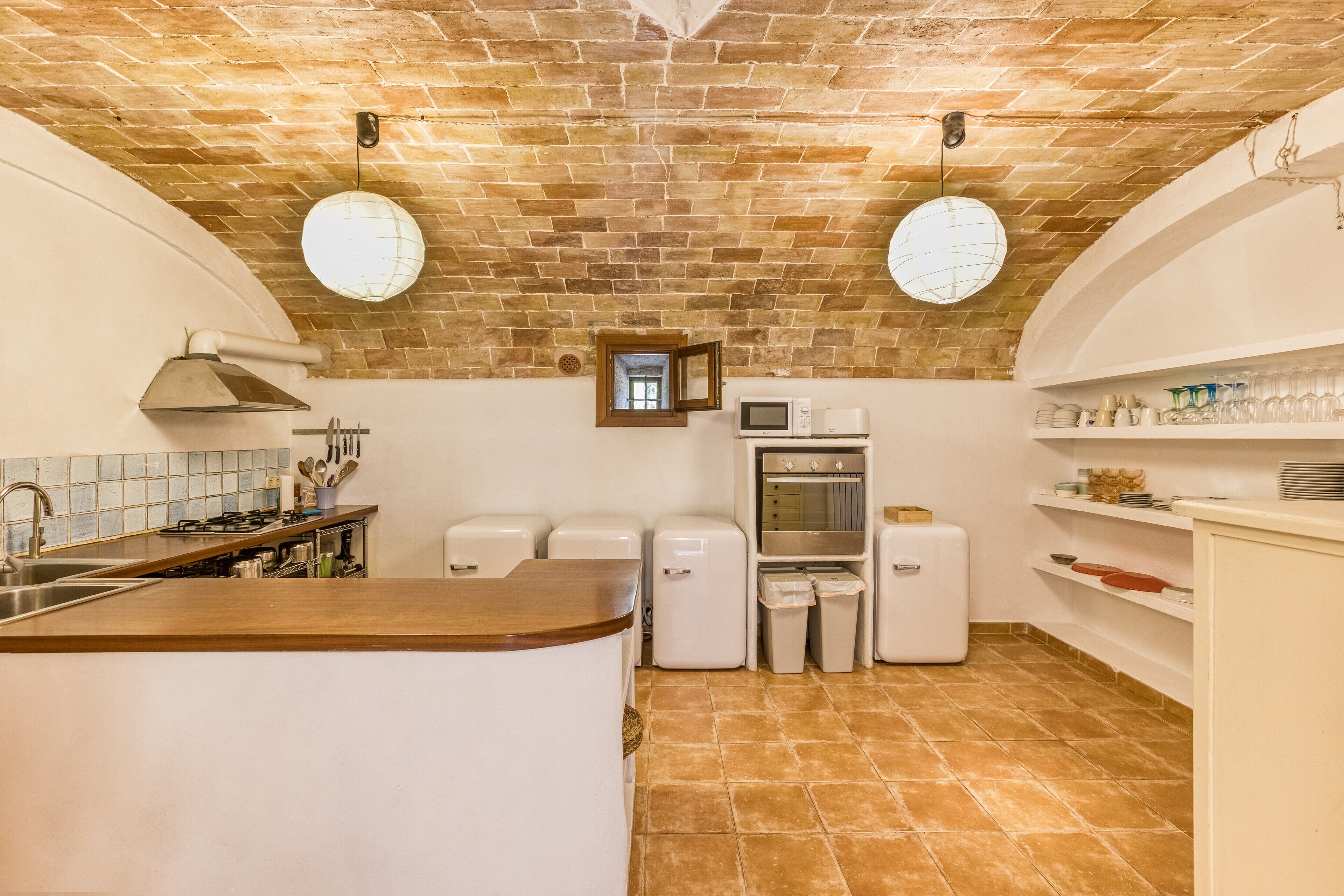 A compact kitchen with a brick ceiling, white cabinetry, a built-in oven, and a microwave.