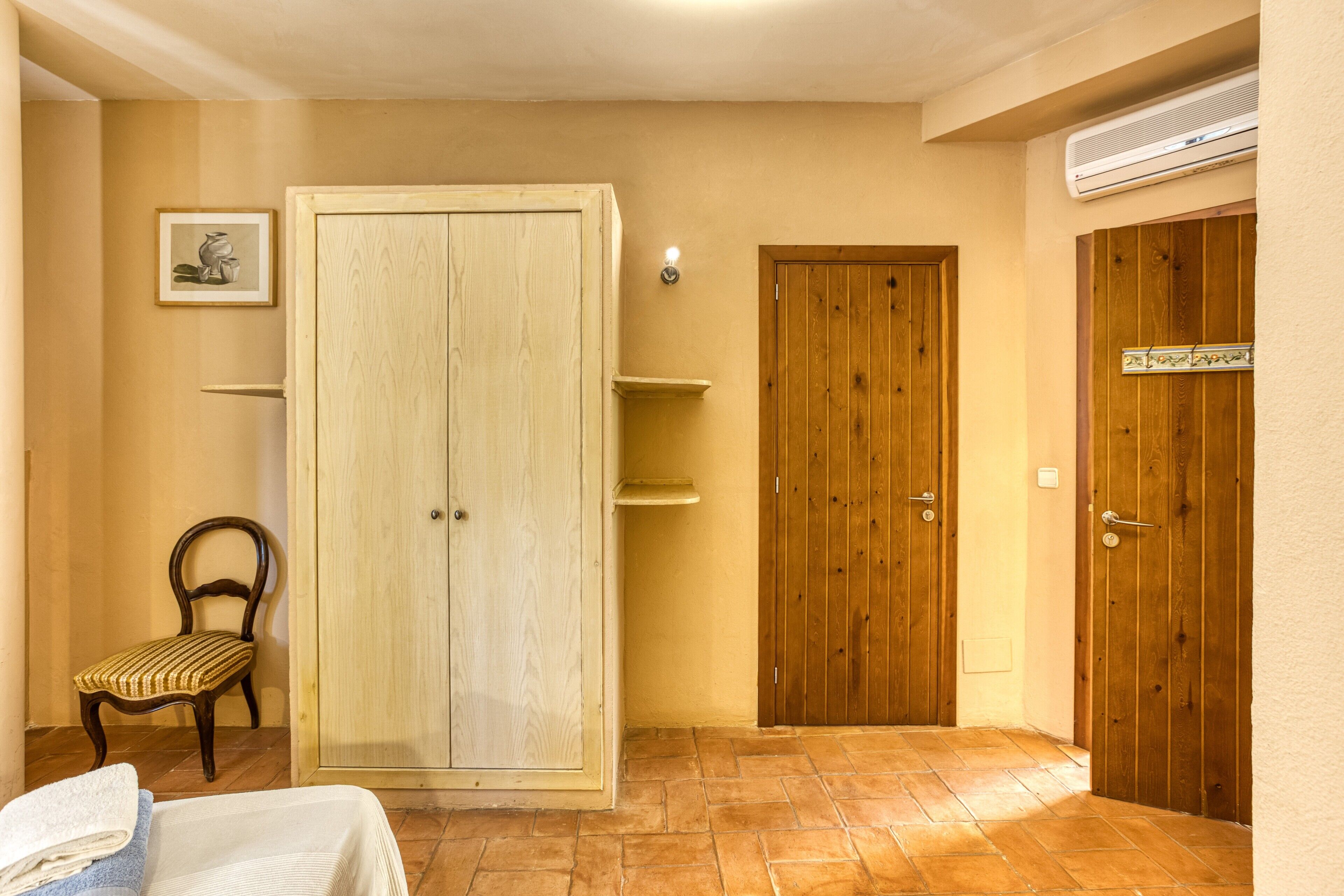 Ein Schlafzimmer mit Bett, Schrank, Stuhl und Tür.