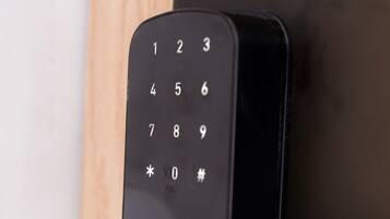 A close-up of a black electronic keypad lock on a door.
