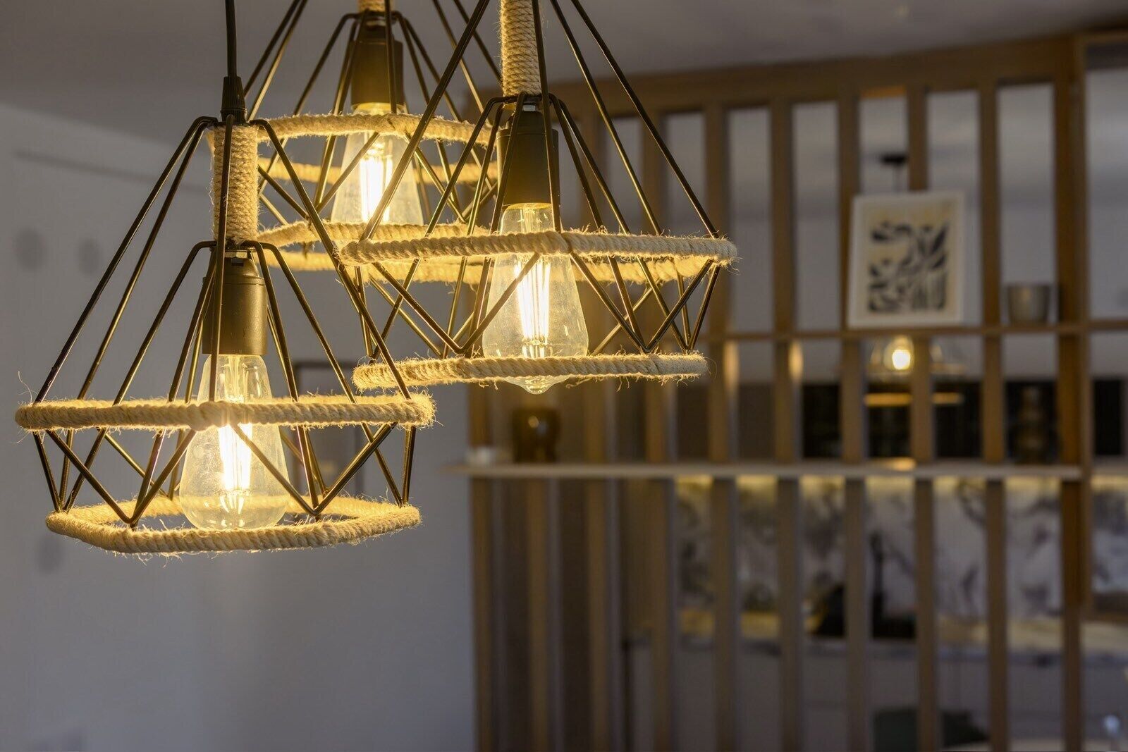 Un interior moderno con lámparas geométricas y un separador de madera.