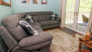Ein Wohnzimmer mit einem grauen Ecksofa, einem gemusterten Teppich und abstrakter Wandkunst.