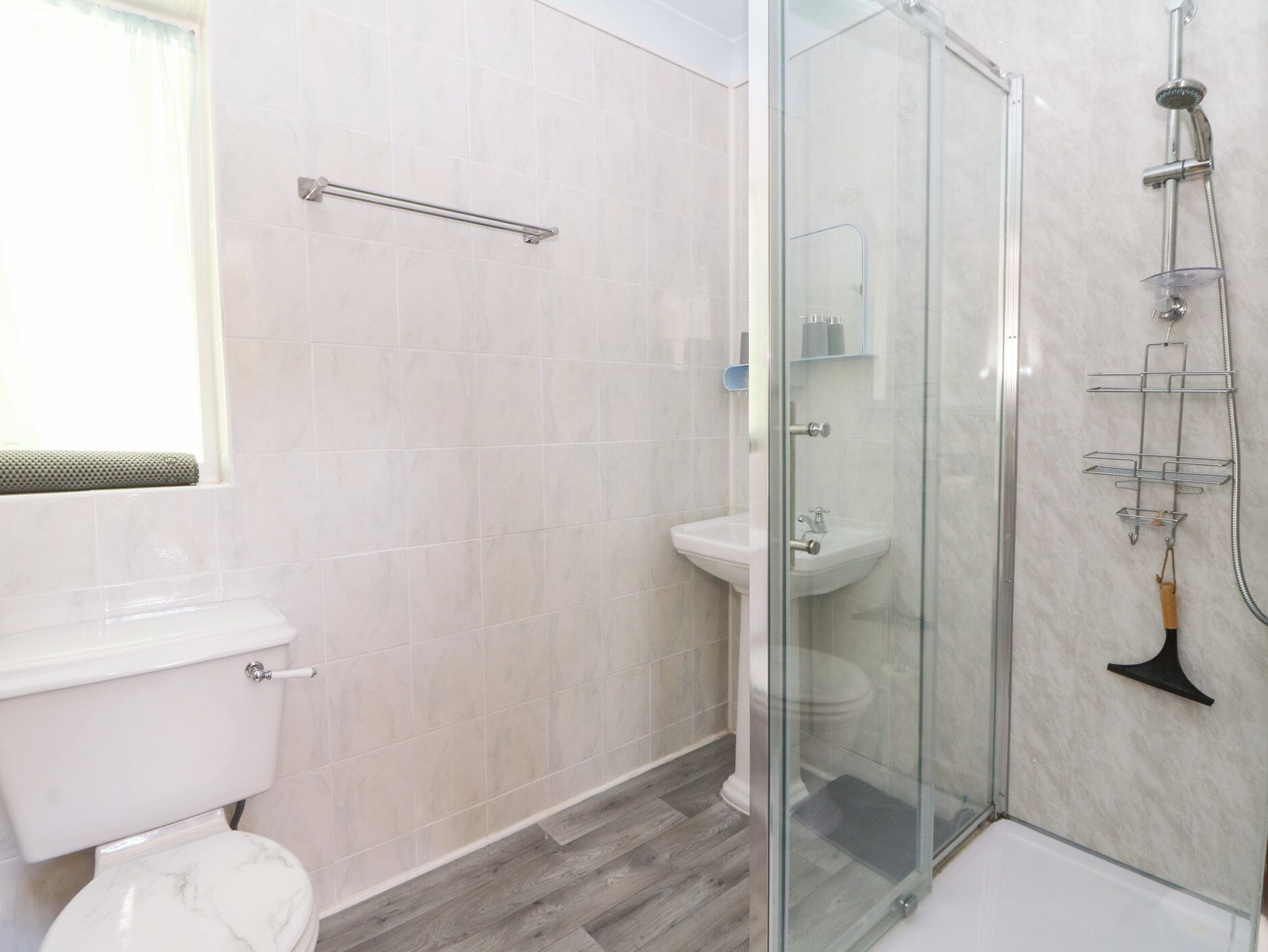 Ein modernes Badezimmer mit Duschkabine aus Glas, Toilette und Waschbecken.