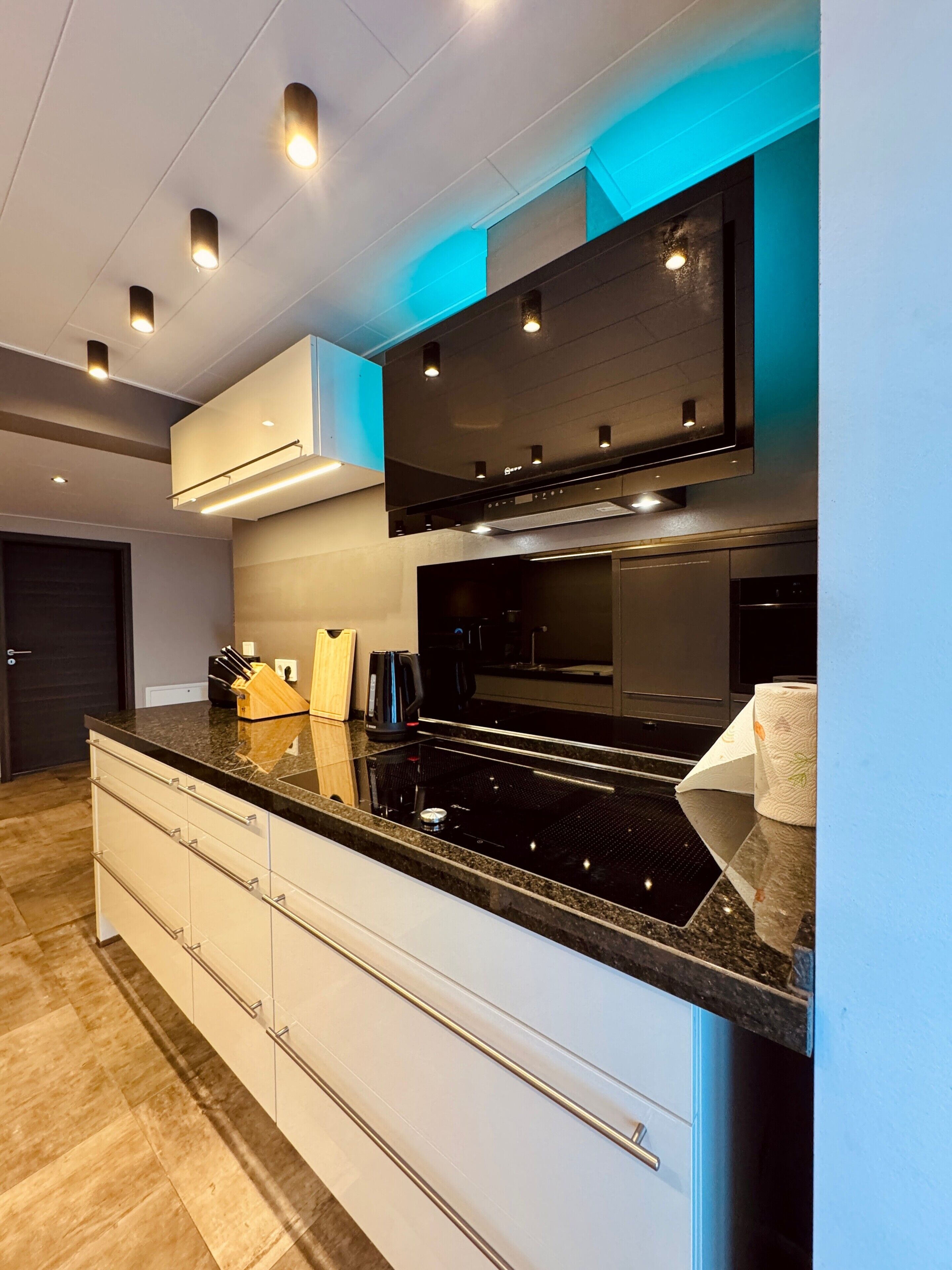 Una cocina moderna con encimera negra, armarios blancos y electrodomésticos integrados.