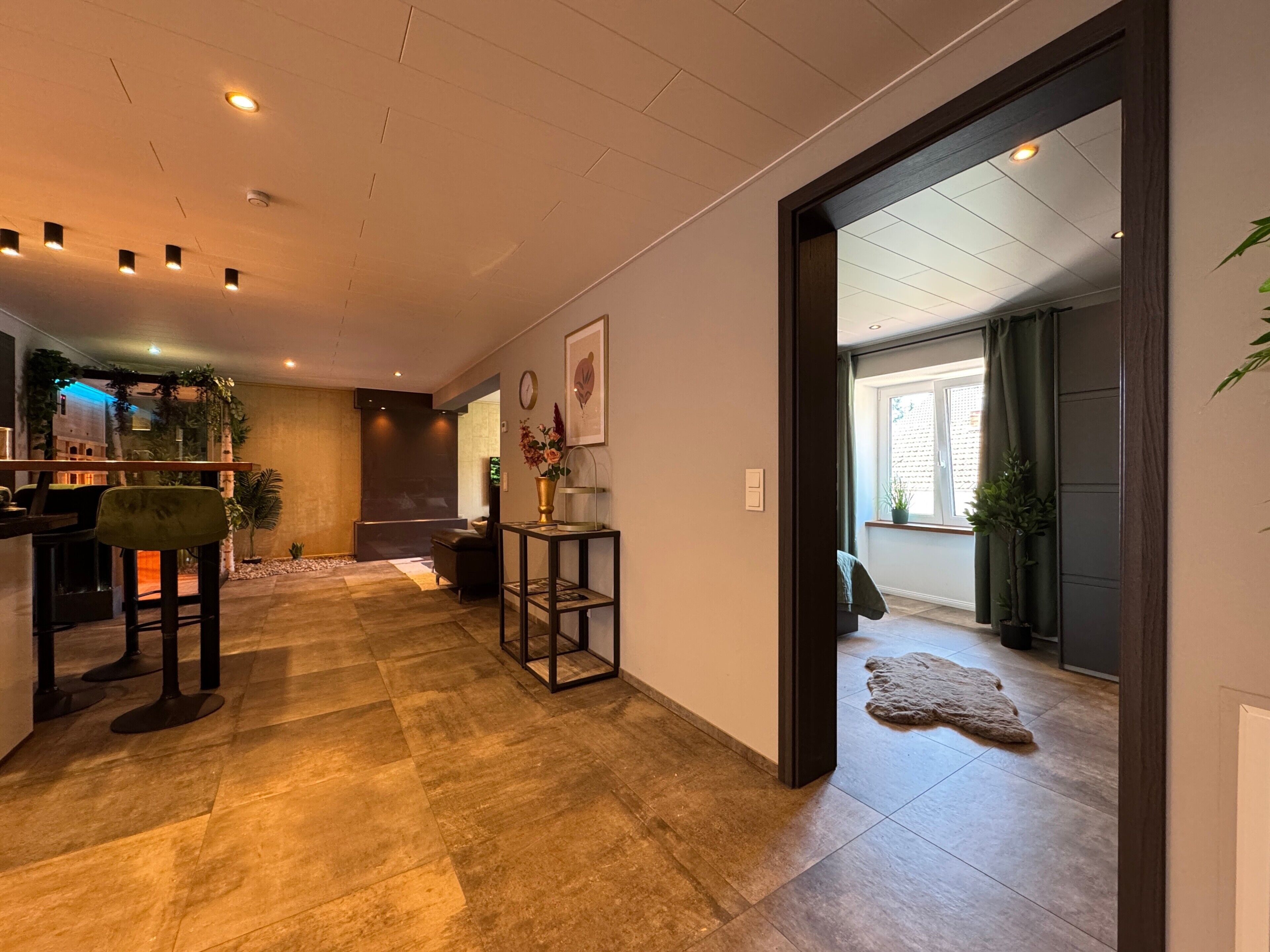 A modern interior with a kitchen area, seating, and a view into another room.