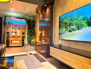 Un hall d’entrée moderne doté d’un grand téléviseur, de touches de décoration en bois et de plantes d’intérieur.