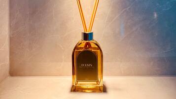 A bottle of OASIS cologne on a shelf with a marble background and a light fixture above.