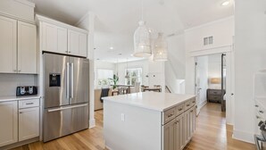 A modern kitchen with white cabinetry, a stainless steel refrigerator, and a central island.