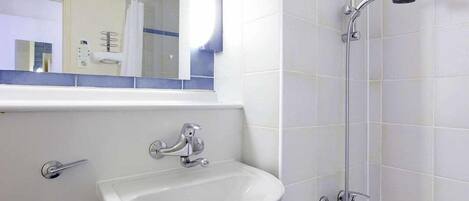 A bathroom with a white sink, a mirror, and a shower.