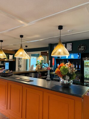 A bar area with a counter, pendant lights, a clock, and a decorative vase. - The Kiln Hotel, Wakefield (West Yorkshire), Part of the AG Collection (Wakefield)