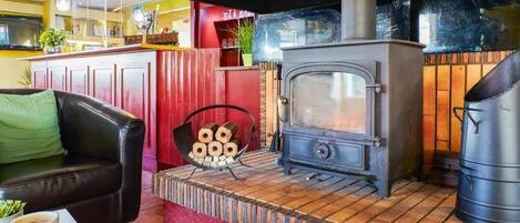 Una habitación acogedora con un horno de madera, un sofá de cuero y una mesa de comedor con pasteles.