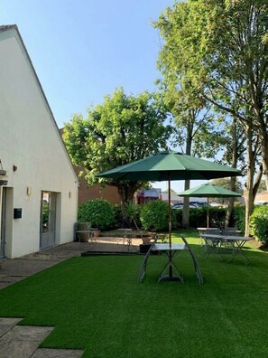 A courtyard with a lawn, outdoor tables, and umbrellas. - The Kiln Hotel, Wakefield (West Yorkshire), Part of the AG Collection (Wakefield)