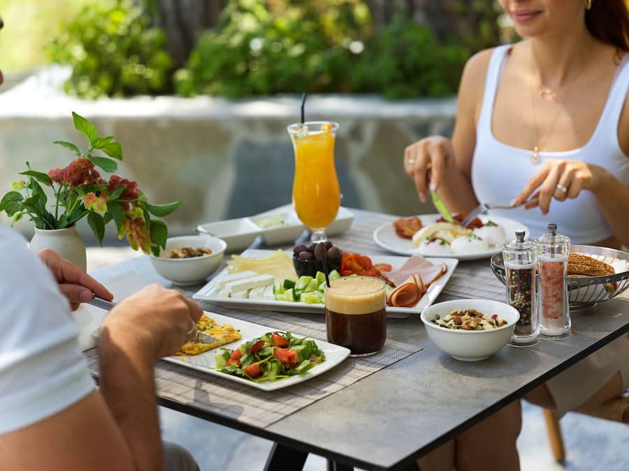 Uma mesa de jantar com diversos pratos, uma bebida e acompanhamentos.