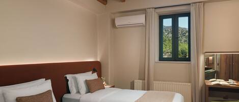 A hotel room with two beds, a wooden ceiling, an air conditioning unit, a window with a view, and a small table with a chair.