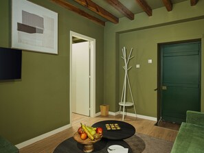 A room with a wooden ceiling, a green door, a coat rack, and a fruit bowl on a round table. - Pine View Boutique Hotel Adults Only (Saittas)