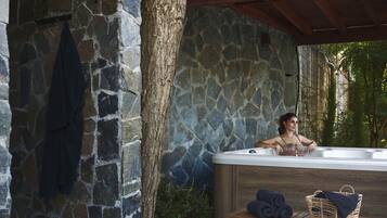 Un muro de piedra con un banco de madera y un jacuzzi.