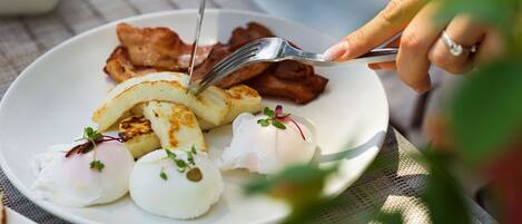Une assiette de nourriture composée d’œufs, de bacon et de pommes de terre.