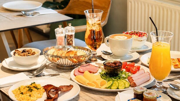 Un buffet de petit-déjeuner proposant divers plats, un coin café et une grande fenêtre donnant sur l’extérieur.
