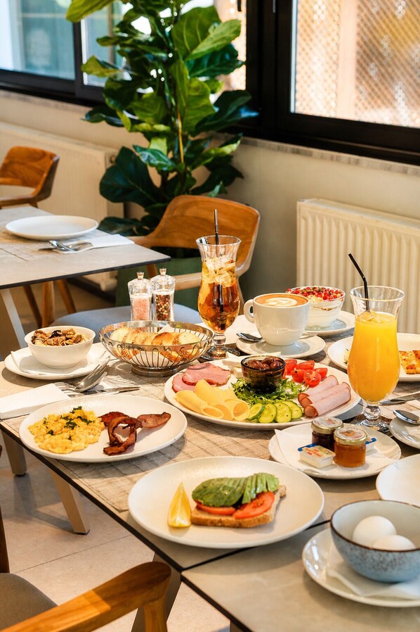 Un bufé de desayuno con diversos platos, una estación de café y un ventanal con vistas al exterior.