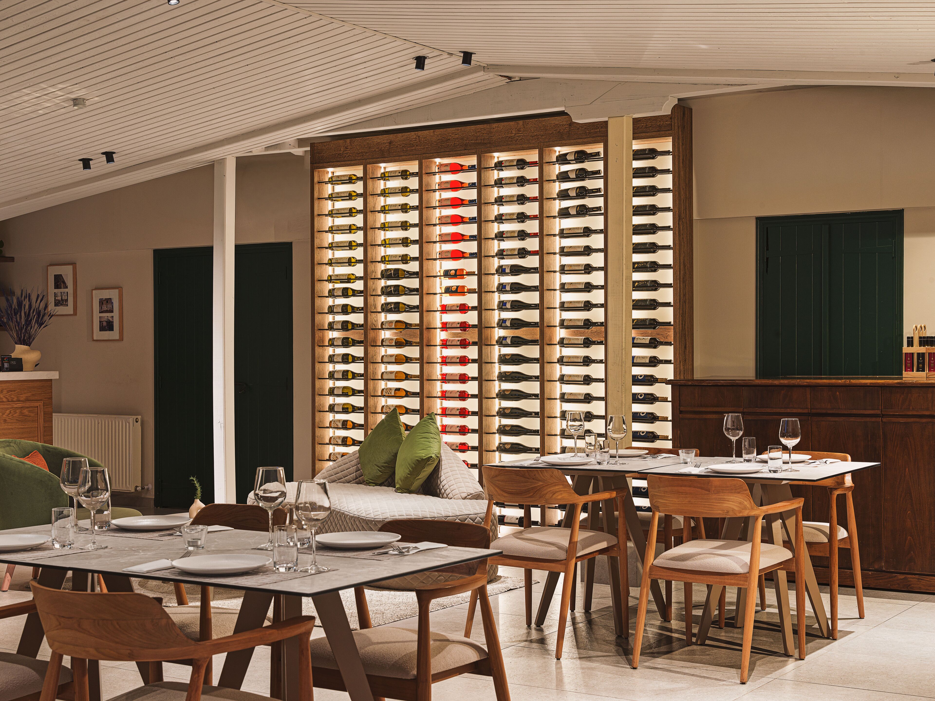 A dining area with a wine rack, wooden furniture, and a green door.