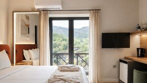 Une chambre d’hôtel avec un lit, un bureau, une télévision et un balcon offrant une vue.