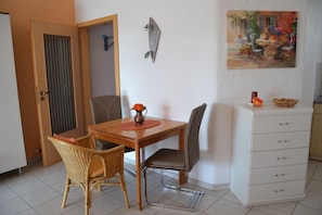 Uma área de refeições com uma mesa de madeira, cadeiras de vime, um armário branco e uma decoração de peixe na parede.