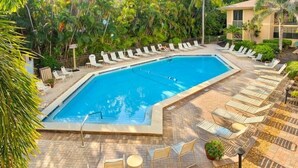 Una piscina rectangular con sillones de descanso y una zona de terraza empavedada.