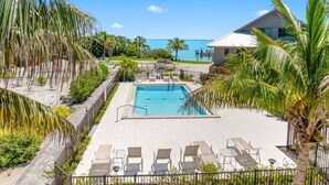 A swimming pool with lounge chairs, surrounded by palm trees and a view of the ocean. - Ventura Captiva 2b 3 Bedroom Condo (Captiva)