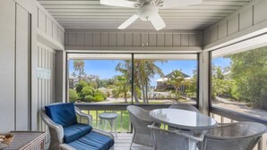 A covered outdoor area with wicker furniture, a ceiling fan, and a view of a landscaped garden. - Ventura Captiva 2b 3 Bedroom Condo (Captiva)
