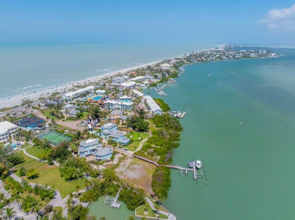 Vista aérea de un complejo turístico costero con puerto deportivo, playa y campo de golf.