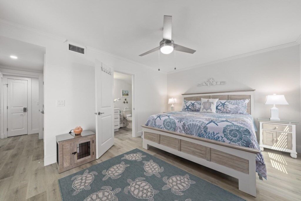 Ein Schlafzimmer mit einem Bett, einem Deckenventilator, einem Nachttisch und einem Teppich.