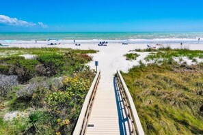 A wooden boardwalk leading to a beach with clear skies and calm waters. - Coquina Beach 2c 2 Bedroom Condo (Sanibel)