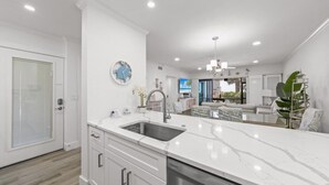 Una cocina moderna con armarios blancos, encimera de mármol y lavavajillas integrado.