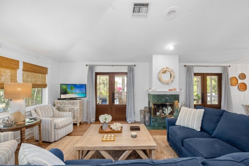 A living room with a sofa, armchairs, a coffee table, a television, and a fireplace.