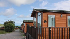 A row of wooden mobile homes with large windows and a paved driveway.
