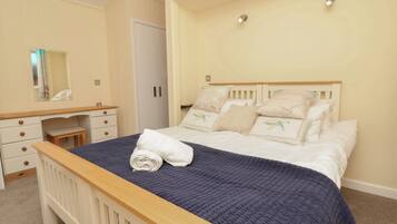 A bedroom with a bed, a nightstand, a dresser, a mirror, and a door.