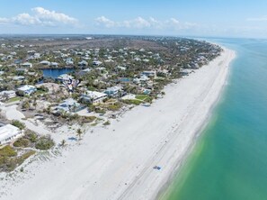 Uma área residencial costeira com casas, uma praia e vista clara para o oceano.