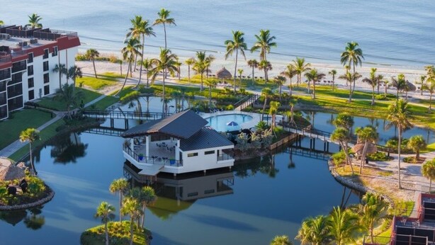 A resort with a pool, palm trees, and a beach view. - Pointe Santo D27 2 Bedroom Condo (Sanibel)